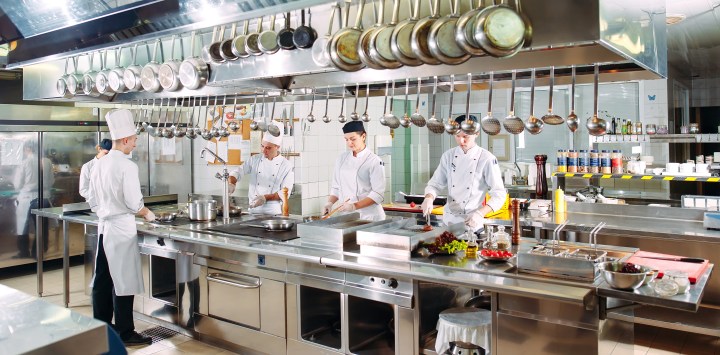 Chefs in a high end restaurant kitchen surrounded by expensive equipment.