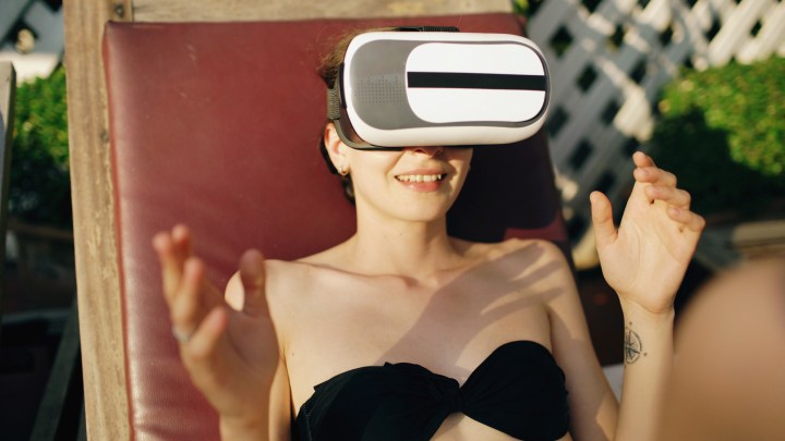 A woman sunbathing while wearing a virtual reality headset.